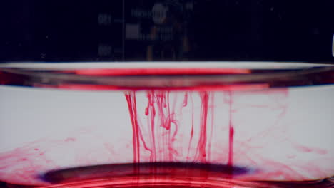 Laborglas-Mit-Blutprobe.-Rotes-Chemisches-Reagenz,-Das-Im-Wasser-Fließt