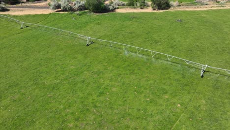 Drone-shot-of-a-sprinkler-system-watering-green-crops-in-the-summer