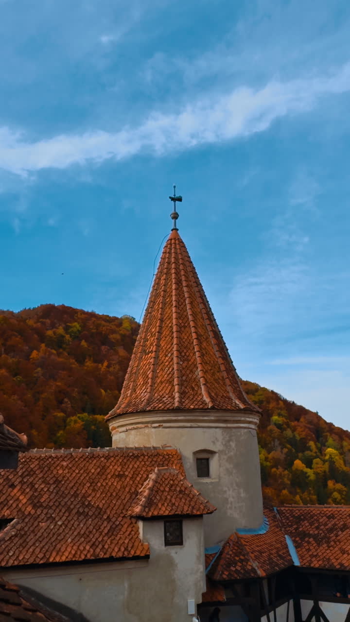 Rooftops of Bran castle in Transylvania, Romania. Colorful autumn nature and blue sky at backdrop. Vertical video