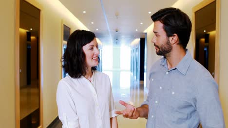Male-and-female-executives-interacting-with-each-other-in-corridor
