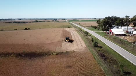 aerial drone footage of a farmer driving a combine harvester in a no-till corn field in rural, midwest iowa farm country