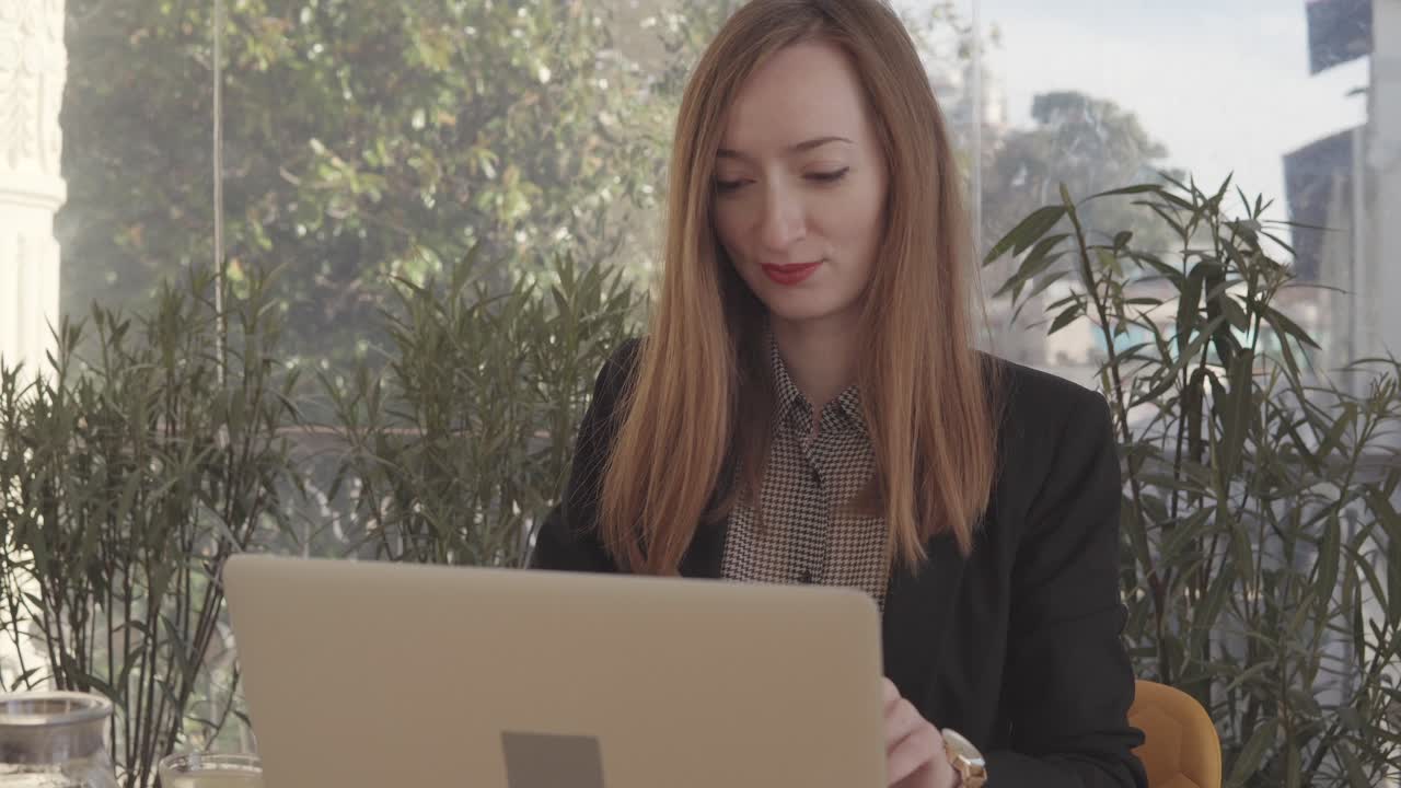 Donna che lavora al computer portatile in un caffè