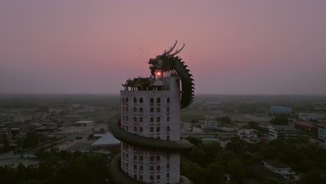 Aerial-drone-backward-moving-shot-of-Wat-Samphran,-Dragon-Temple-in-the-Sam-Phran-District-in-Nakhon-Pathom-province-near-Bangkok,-Thailand-at-sunset