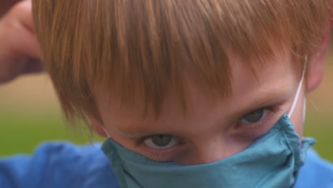 little boy puts on a fabric mask to protect against coronavirus disease