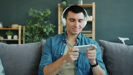 man playing mobile game on couch