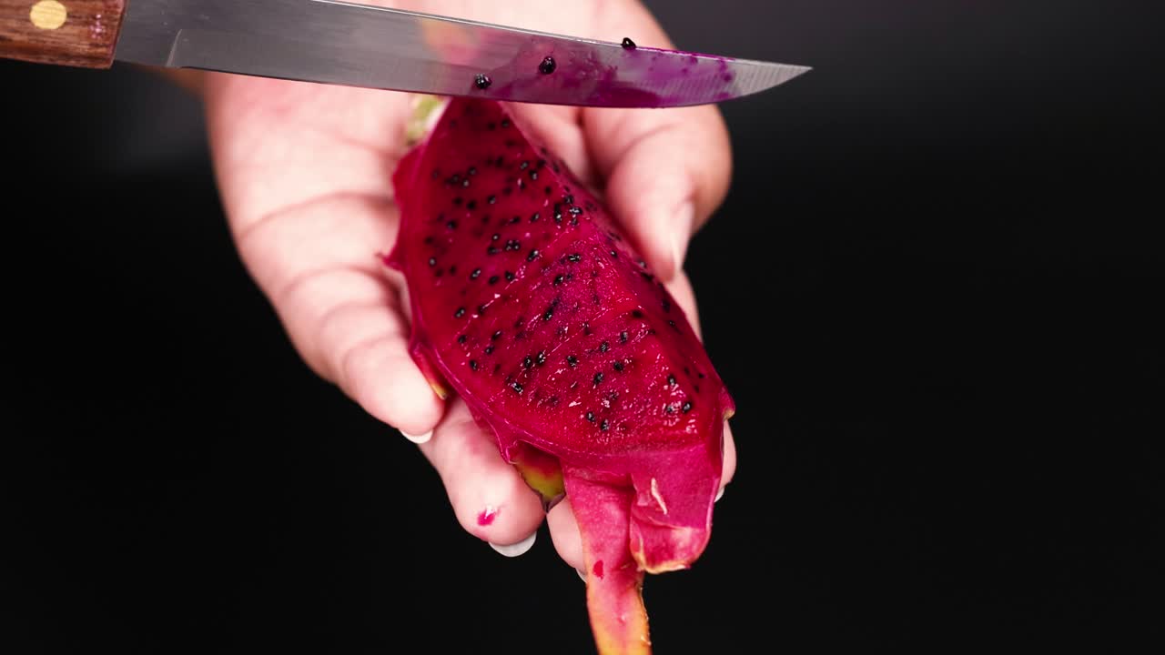 cortando a mano la fruta del dragón con un cuchillo
