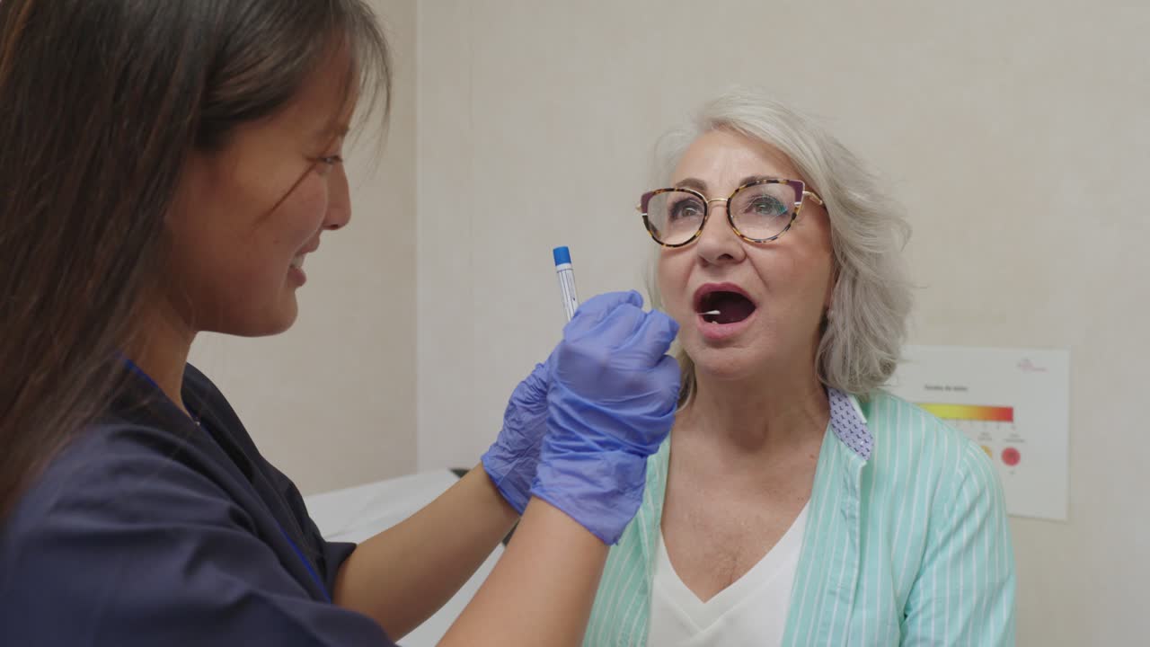 Senior woman getting a throat swab by a doctor