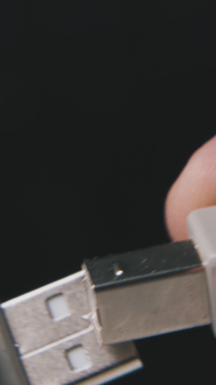 young person shows different kinds of usb plugs with grey cables on black background extreme close view