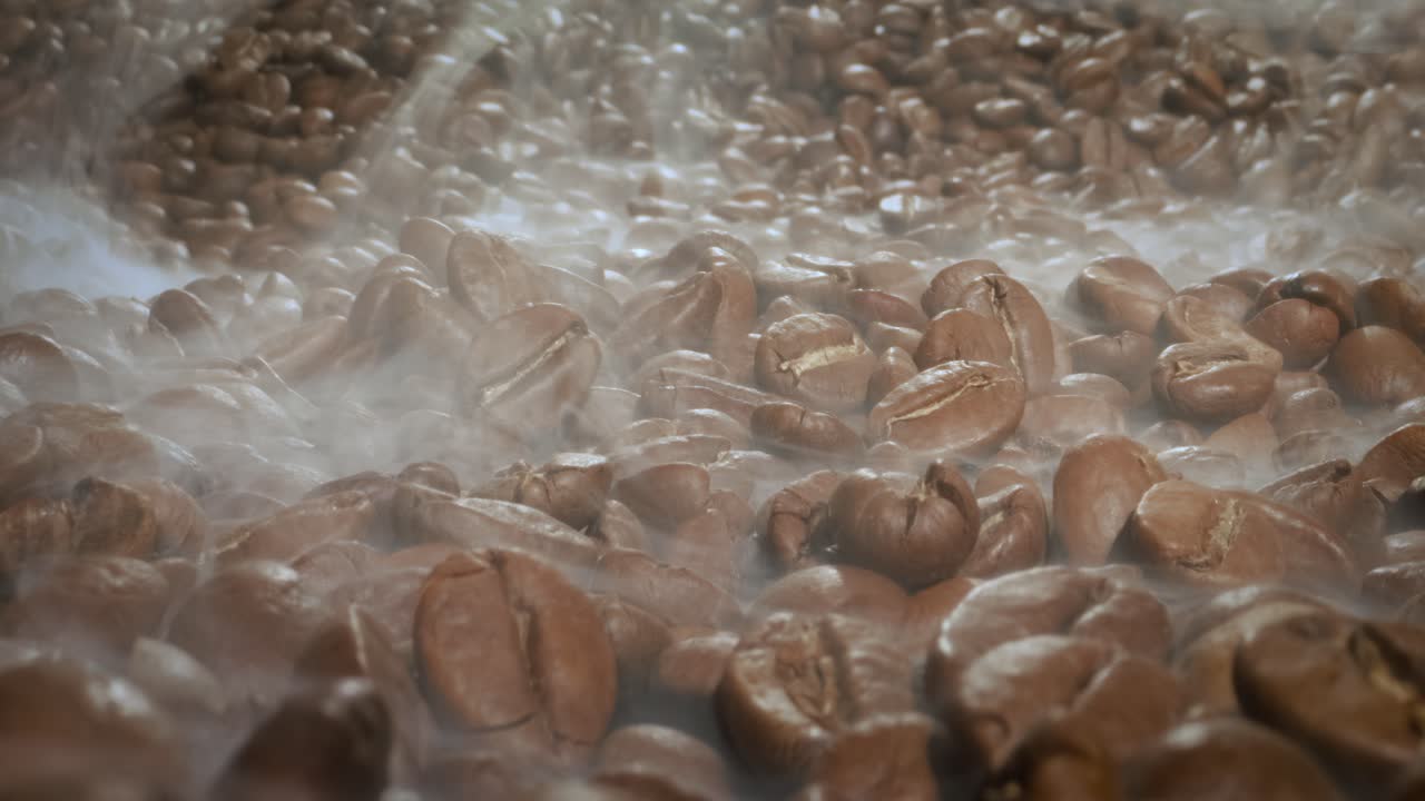 Close up of seeds of coffee. Fragrant coffee beans are roasted smoke comes from coffee beans.