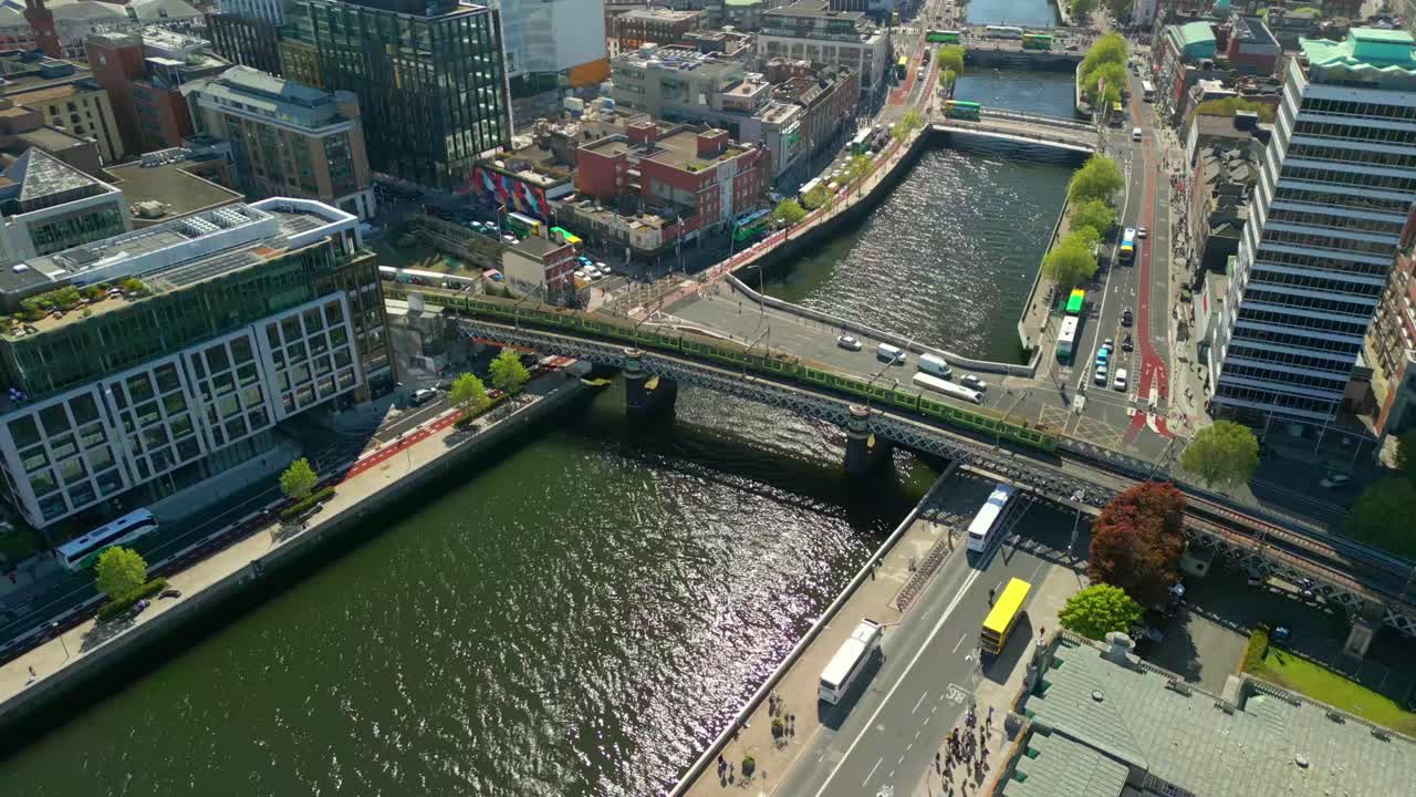 A train passing over the River Liffey, next to Dublin Custom House Quay in Dublin City Centre, Lenister, Ireland on a bright and sunny day. Filmed in 4K, 60FPS and with Rec709 color.