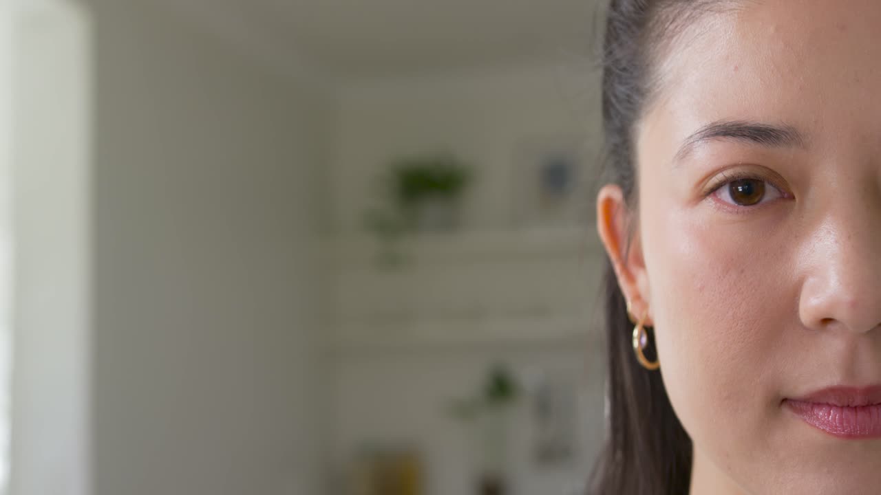 Reagendo alla luce, donna afroamericana che apre gli occhi sorridendo con orecchini a cerchio d'oro a casa, con spazio per il testo