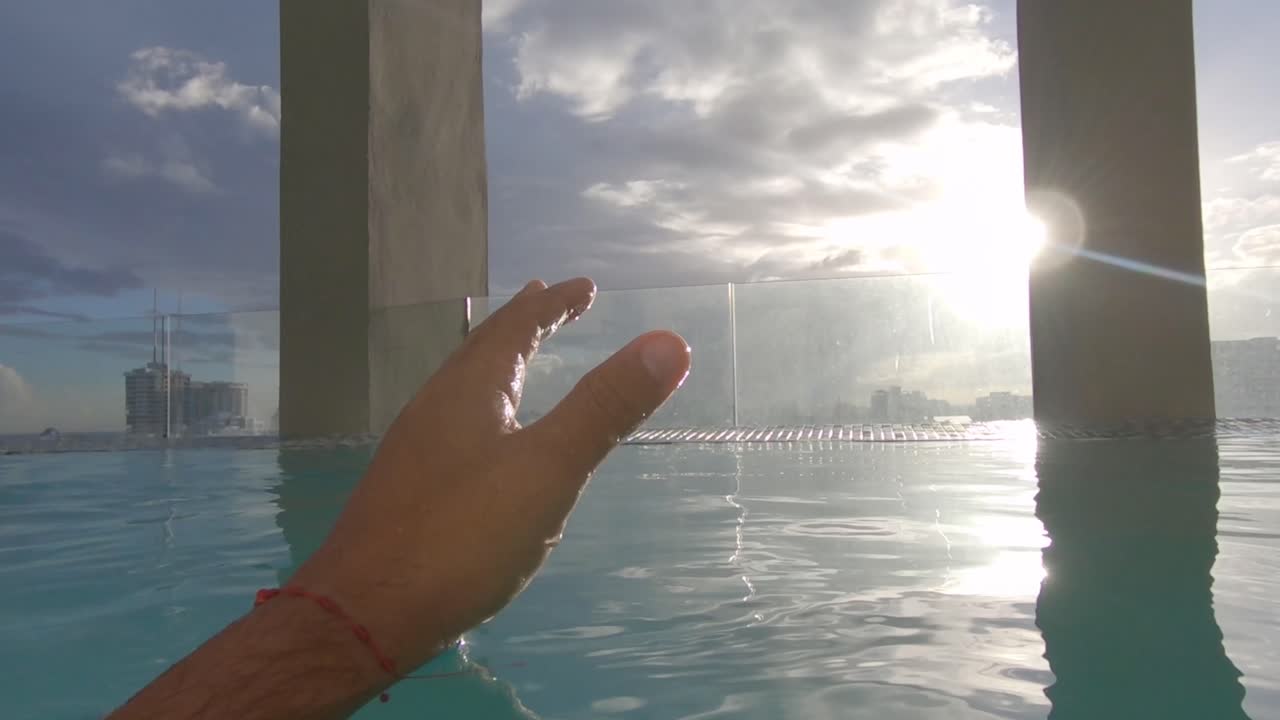 Young hand caresses the water of a swimming pool on a sunny day in summer, UHD, 60fps, gopro, realtime, cinematic