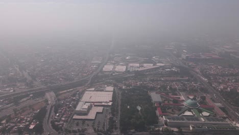 flight over mexico city in a  very polluted day, the old lecumberri prison is visible in the scene