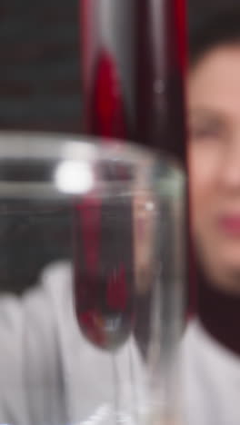 lab assistant with magnifying glass takes tube with red liquid to check condition in lab slow motion. probe lens footage of experiment result closeup