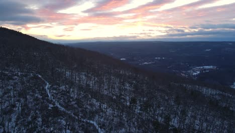 drone footage of a forested mountain covered in light snow during winter at dusk in the appalachian mountains