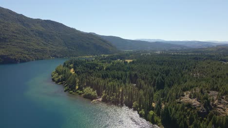 Aerial-dolly-in-of-turquoise-Epuyen-lake-between-pine-trees-and-mountains,-Patagonia-Argentina