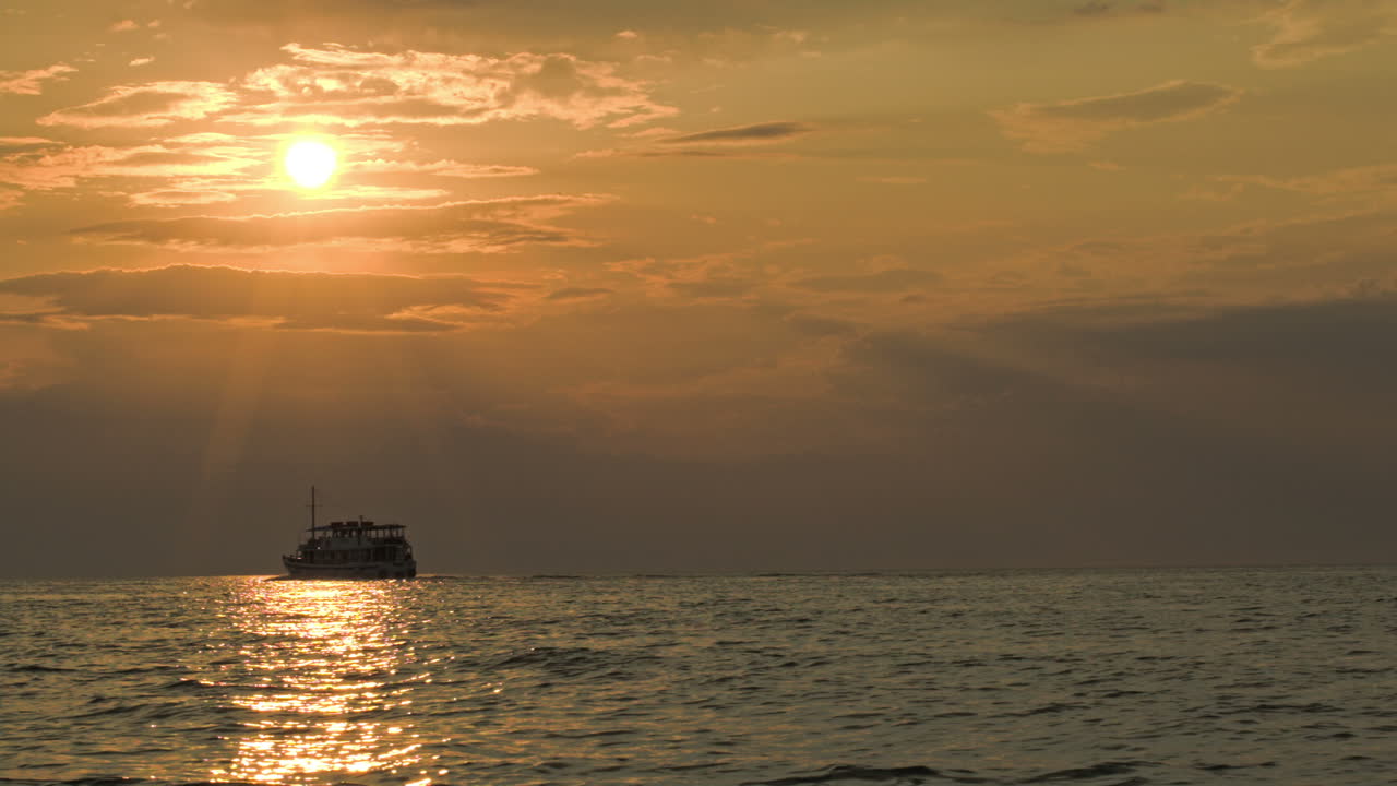 해가 지는 동안 조용한 바다에서 항해하는 배