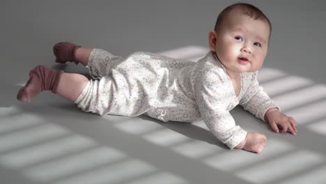 happy baby smiling while lying on his stomach - tummy time - full-body shot