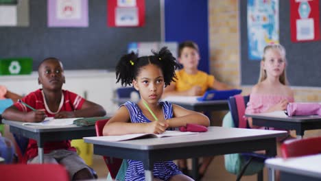 diverse schoolchildren sitting in classroom raising hands to answer questions during lesson