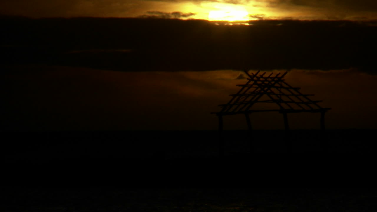 Il sole tramonta in una giornata nuvolosa su una capanna alle Hawaii
