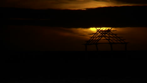 the sun sets on a cloudy day over a hut in hawaii