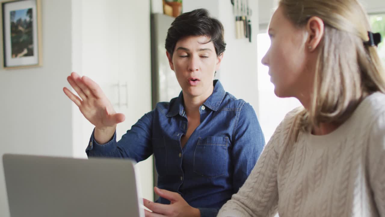 백인 레즈비언 커플이 집에서 노트북을 사용하여 재정을 함께 계산합니다.