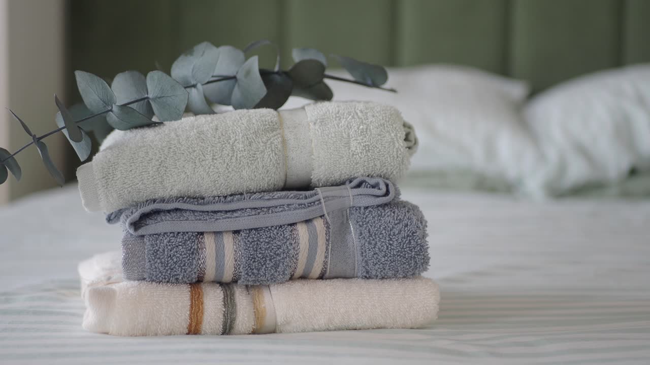 Stack of towels on a bed with eucalyptus