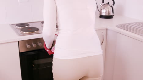 blonde woman getting dish out oven