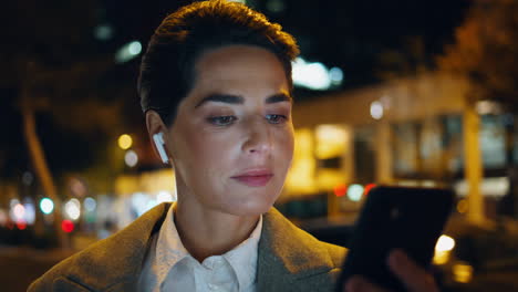 mujer de negocios mirando pantalla de teléfono inteligente en closeup nocturno. mujer relajada escuchar