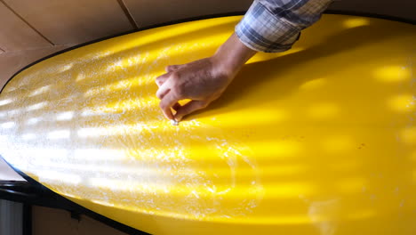 surfer maintain surfboard by applying wax, pov close up