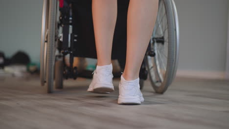 legs of young woman pushing wheelchair with patient with disability