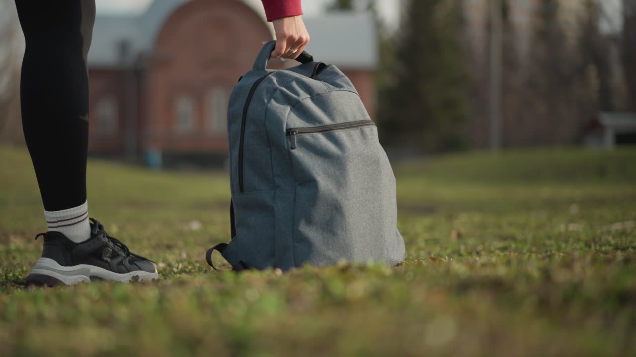 Sneakers On Field, Footwear Resting On Grassy Area Near Bag, Athletic Sneakers Shown With Backpack In Grassy Environment, Closeup Of Sports Shoes And Backpack On Grassy Surface During Walk