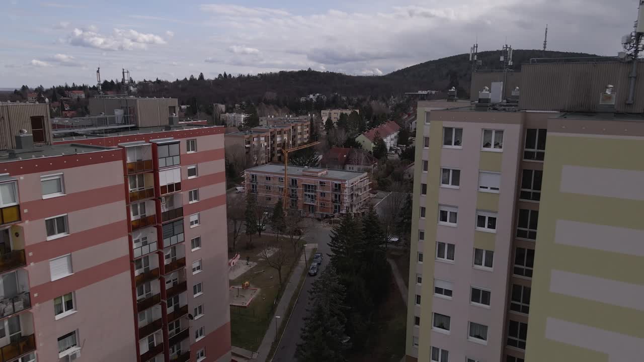An aerial view of high-rise residential apartment buildings with a surrounding urban landscape. Flying between two flat with a drone.