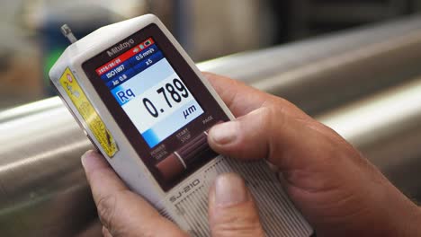 quality manager using roughness measuring device to inspecting,checking steel in factory.