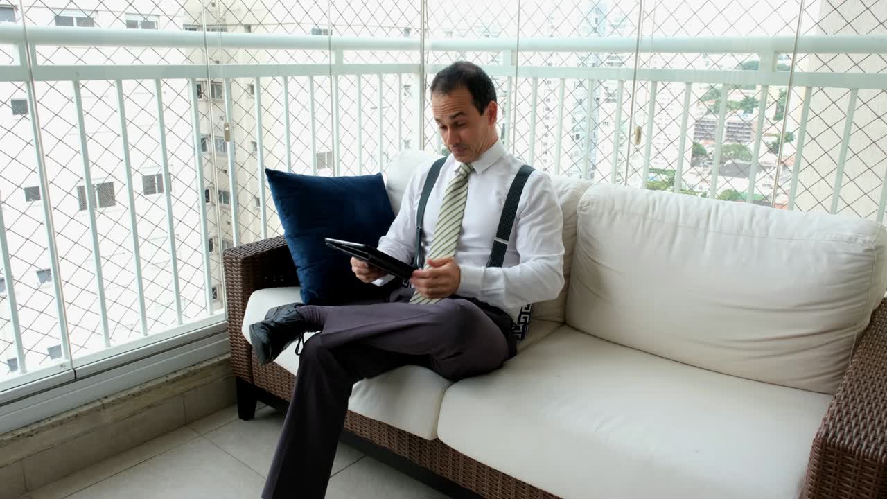 타이와 서펜서를 입은 남자가 태블릿을 보고 좋은 소식을 축하하고 있습니다.