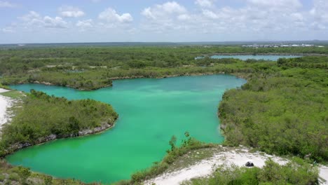 Toma-Aérea-Con-Drones-En-El-Lago-Azul,-Cap-Cana-República-Dominicana-Con-Vistas-A-Las-Aguas-Azules,-Carro-De-Golf-De-Cielo-Despejado-Pasando-Por-El-Sendero