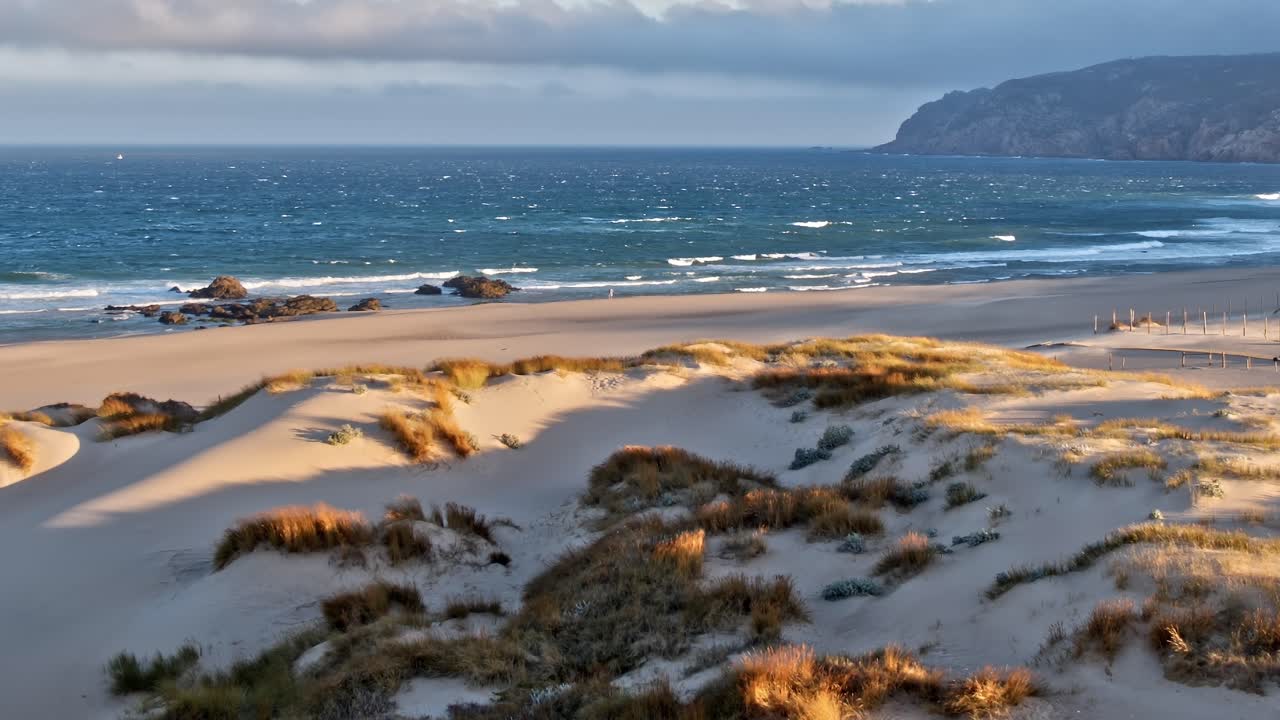 Aerial view of sand dunes and ocean in Portugal at sunset hour