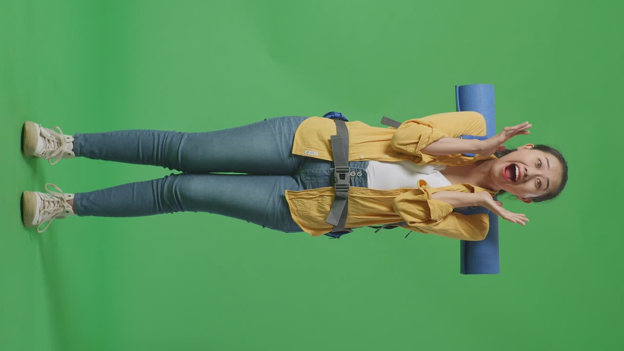 cuerpo lleno de excursionista femenina asiática con mochila de montañismo diciendo wow mientras estaba de pie en el fondo de la pantalla verde en el estudio