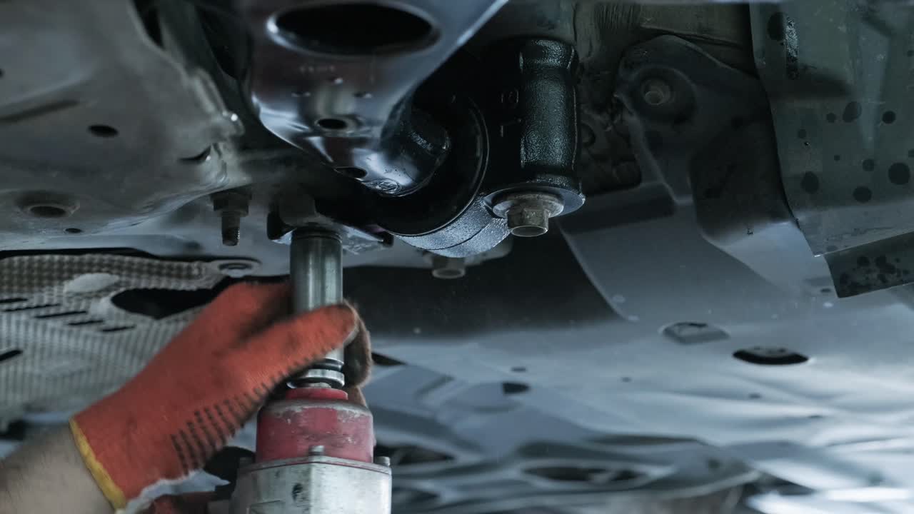 mecánico de automóviles que trabaja debajo de la máquina de elevación de automóviles en el garaje. reparación de autos