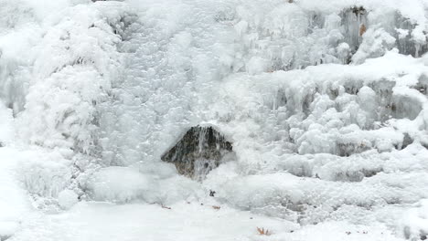 Frozen-waterfalls-form-a-small-cave-showing-water-flow-underneath