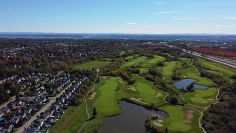 Genießen-Sie-An-Einem-Sonnigen-Herbsttag,-Aufgenommen-Von-Einer-Drohne,-Atemberaubende-Luftaufnahmen-Eines-Golfplatzes-In-Quebec,-Der-An-Ein-Bezauberndes-Viertel-Angrenzt