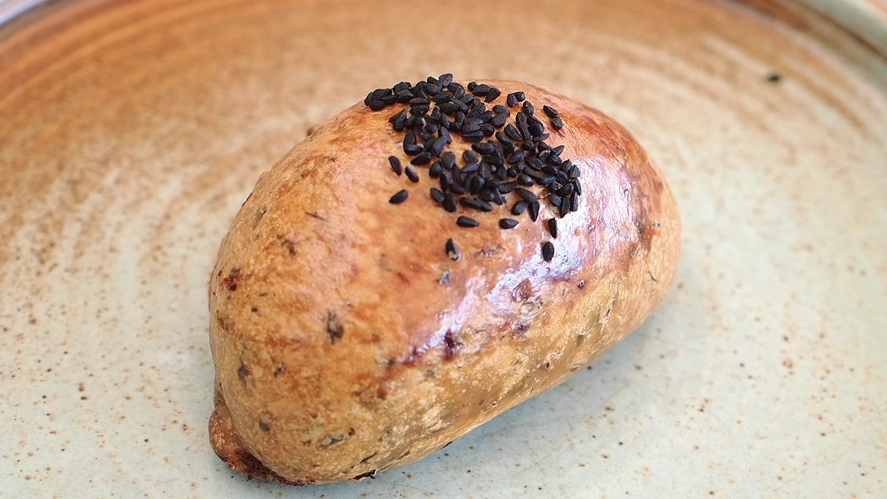 Hand Picking Up a Sesame Seed Bun from a Plate