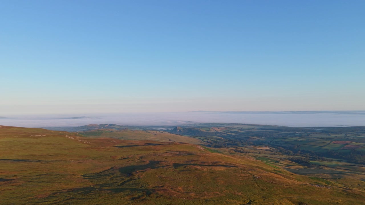 Paesaggio di brughiera aperta all'alba nel Galles del Sud sui Brecon Beacons. Castello di Carreg Cennen e nebbia che avvolge i campi in lontananza.