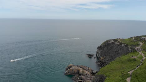 boat sailing by the sea and large green rocky mountain