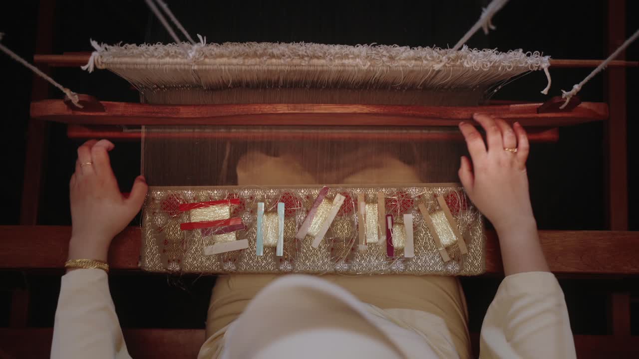 Top down weaver weaving a piece of pua kumbu traditonal fabric on a loom in dramatic lighting