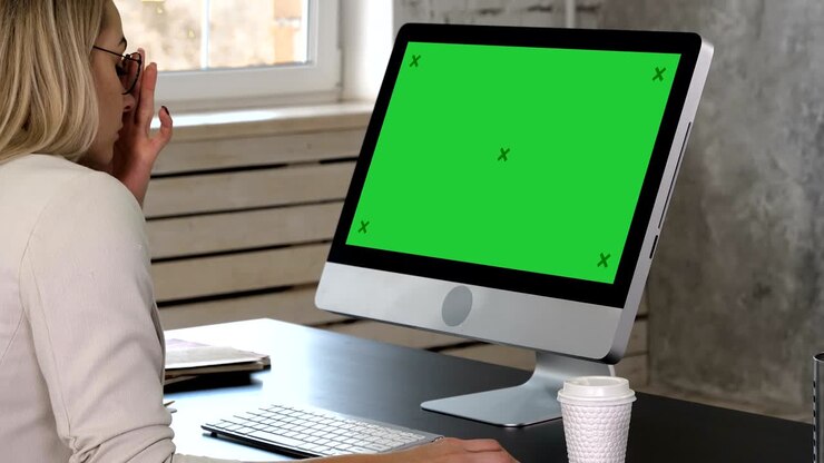 Træt forretningskvinde ved sit skrivebord foran en skærm. Green Screen mock-up-skærm