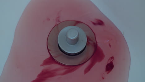 close-up of blood and water washing down a shower drain