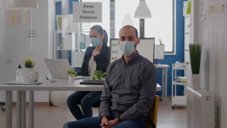 retrato de un hombre de negocios sentado en un escritorio con una máscara médica