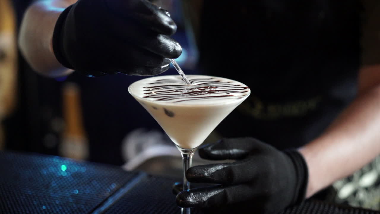 Barman che decora un cocktail con cioccolato liquido.