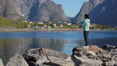 woman fishing on fishing rod spinning in norway.